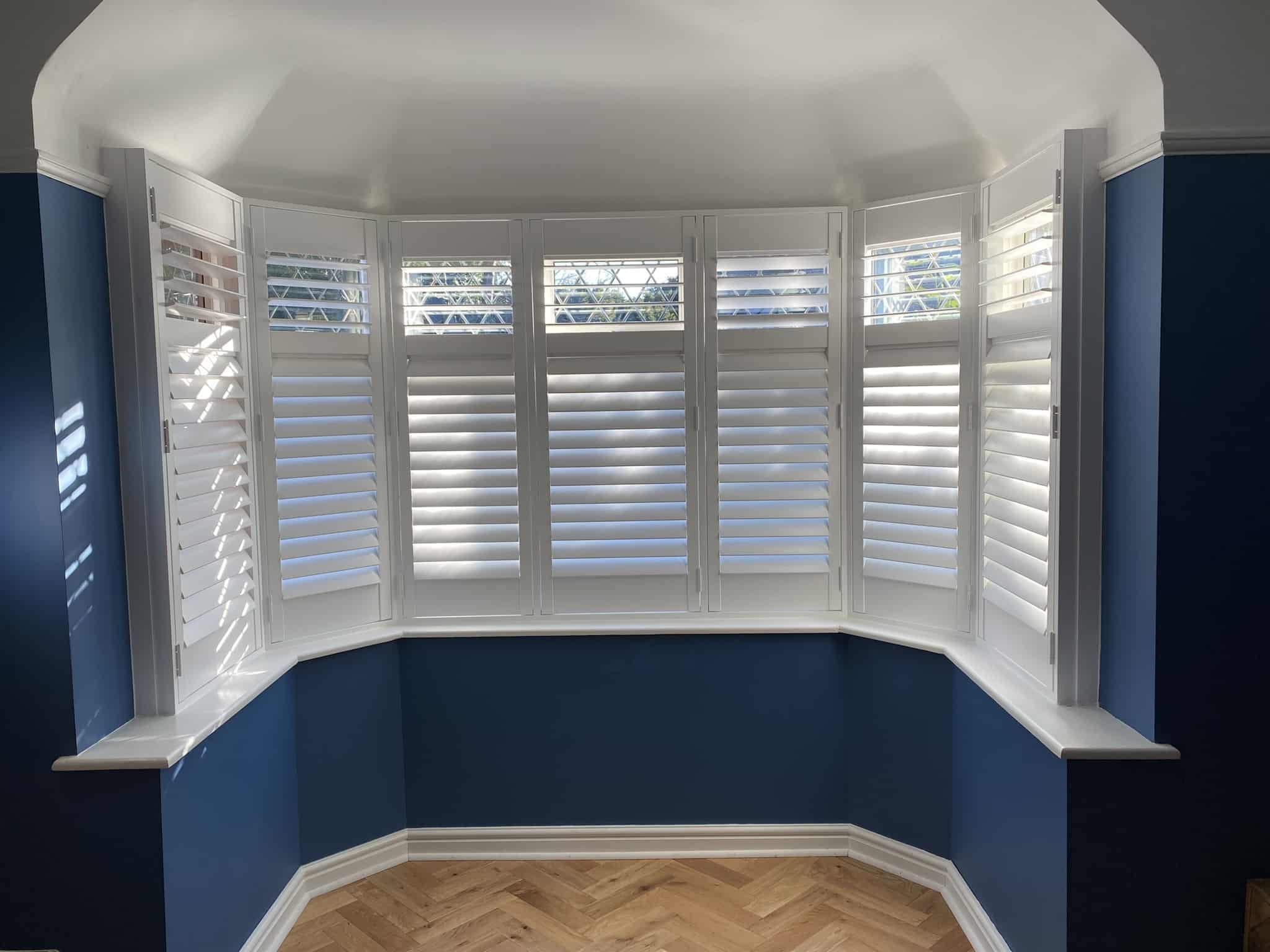 White shutters fitted around a striking bay window