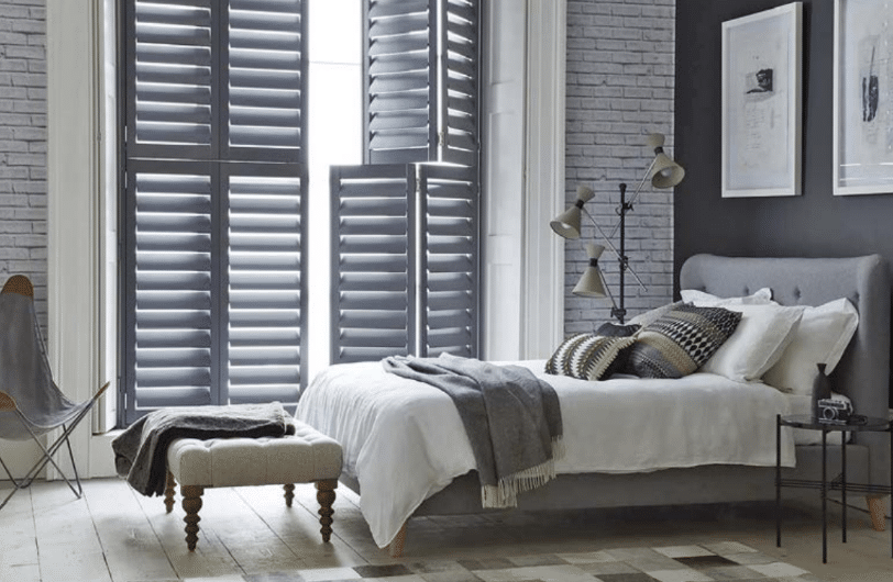 Dark plantation shutters fitted in a stylish bedroom